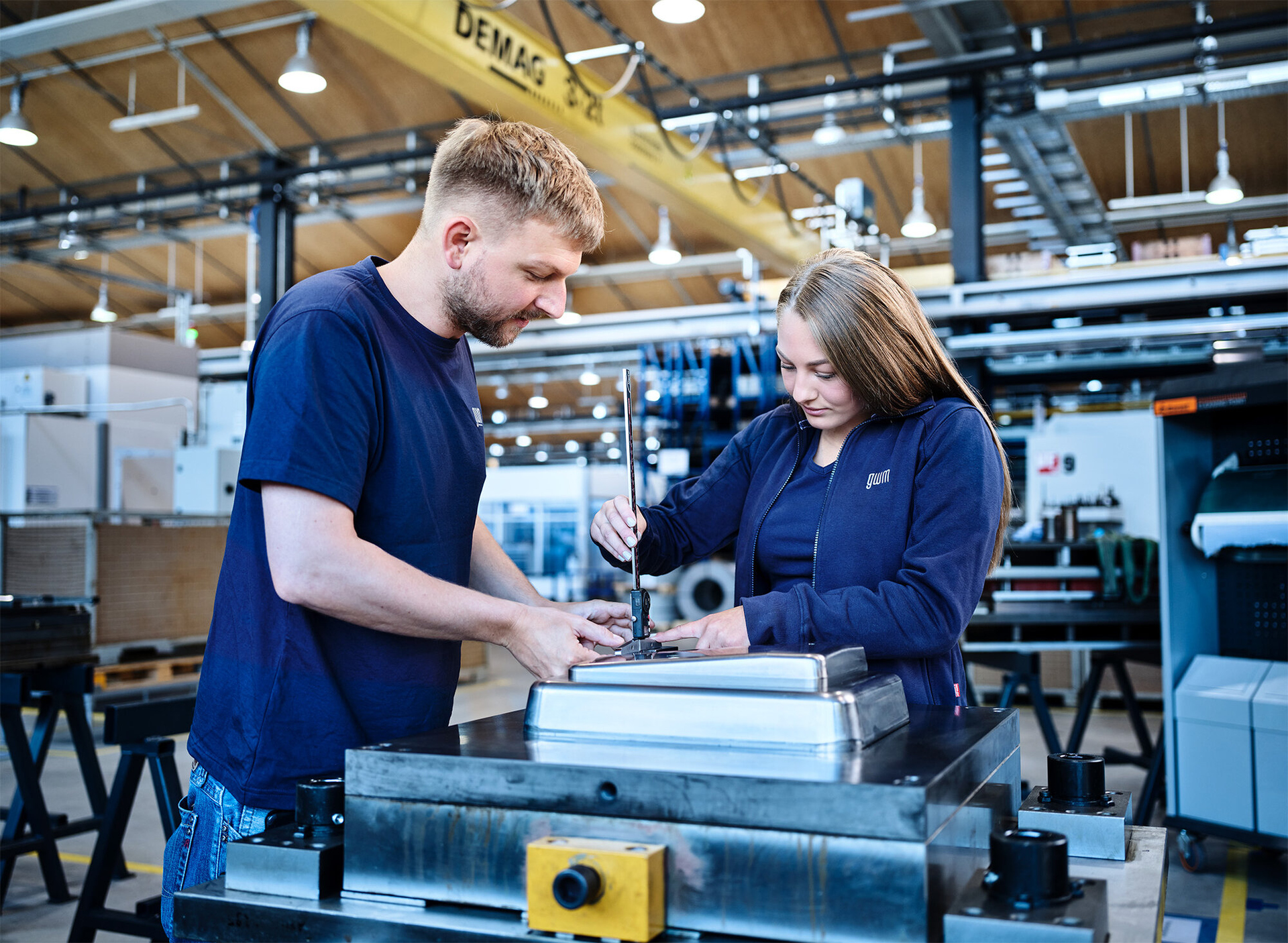Lehrlingsausbilder unterstützt Lehrling bei Metallbearbeitung